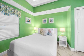 A bedroom with a bed, two bedside tables, a window with blinds, and a door. - Beach Chic Condo On Okaloosa Island Gulfside Pool & Exercise Room (Fort Walton Beach)