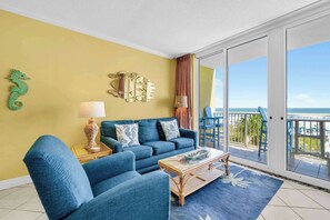 A living room with a sofa, armchairs, a coffee table, a lamp, and a decorative seahorse. - Beach Chic Condo On Okaloosa Island Gulfside Pool & Exercise Room (Fort Walton Beach)