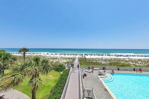 Ein Resort mit Schwimmbad, Blick auf den Strand und einer Holzterrasse, die zum Strand führt.
