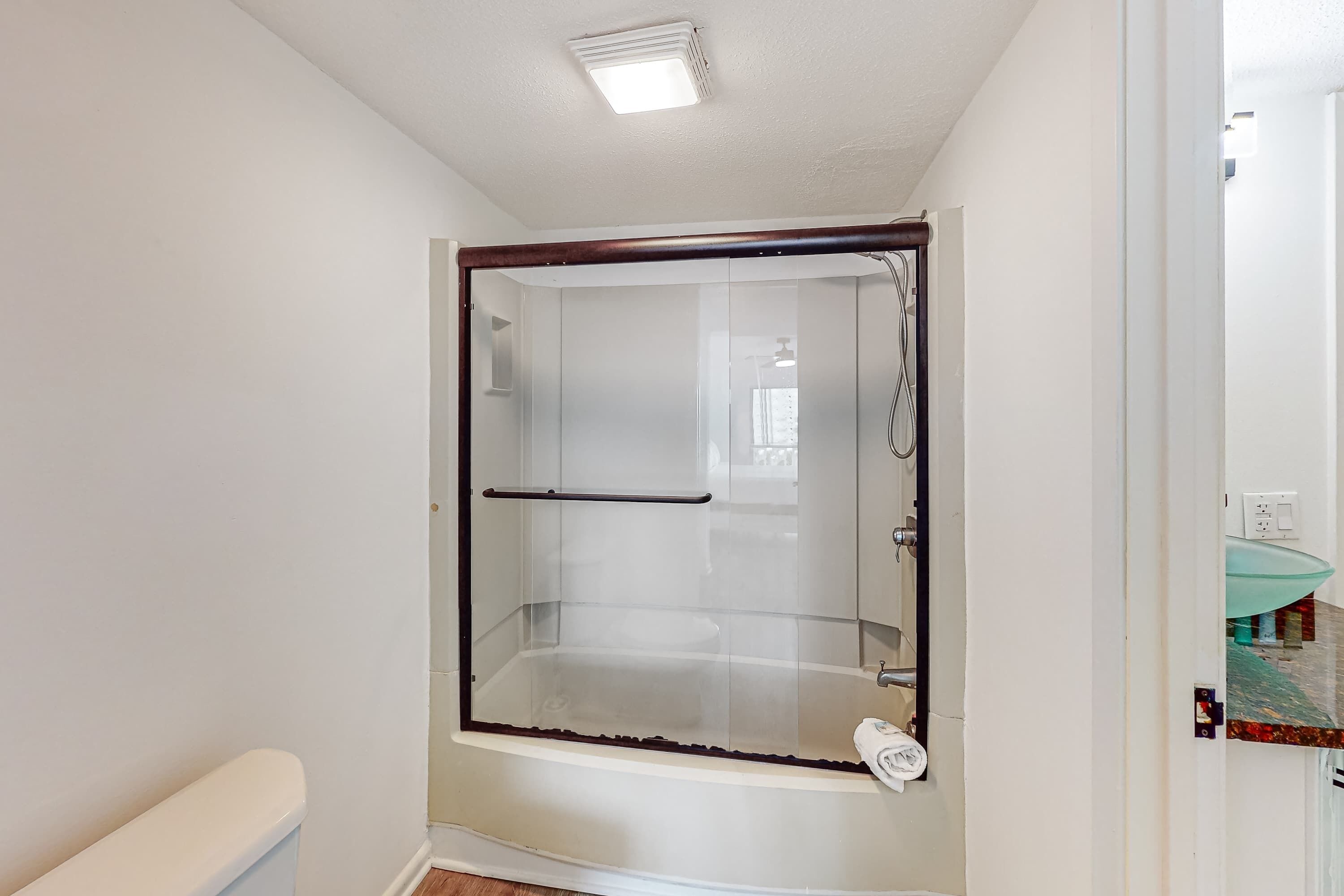 Een moderne badkamer met een douchecabine van glas, een wit toilet en een glazen wastafel.
