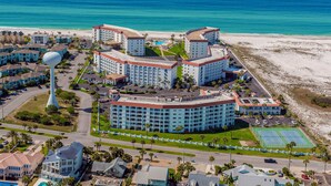 Ein Hotel an der Küste mit mehreren Gebäuden, einem großen Wasserturm und Blick auf den Strand.