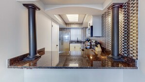 Eine moderne Küche mit Granit Arbeitsplatten, Edelstahlgeräten und einer gemusterten Spritzschutzwand.