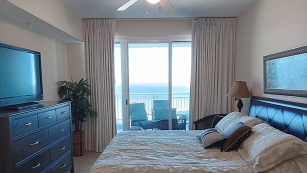 Ein Hotelzimmer mit Bett, Fernseher, Schreibtisch und Blick aufs Meer.