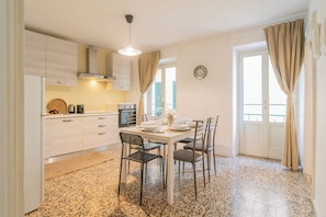 A modern kitchen with white cabinets, a granite countertop, and a dining area with a white table and chairs.