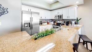 Una cocina moderna con armarios blancos, electrodomésticos de acero inoxidable y encimera de granito.