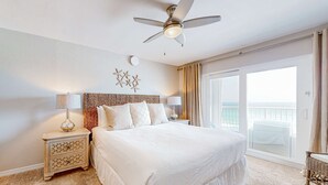 Un letto grande con una testiera, una ventola a soffitto e un comodino con una lampada.