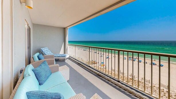 Un balcone con vista sulla spiaggia, arredi in vimini e una ringhiera.