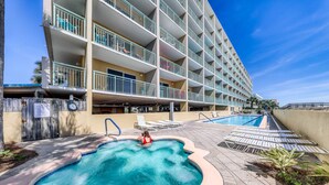Um hotel com piscina, várias varandas e vista para o mar.