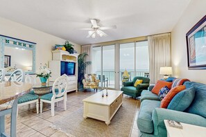 Un salon spacieux avec balcon, un coin repas et un téléviseur.