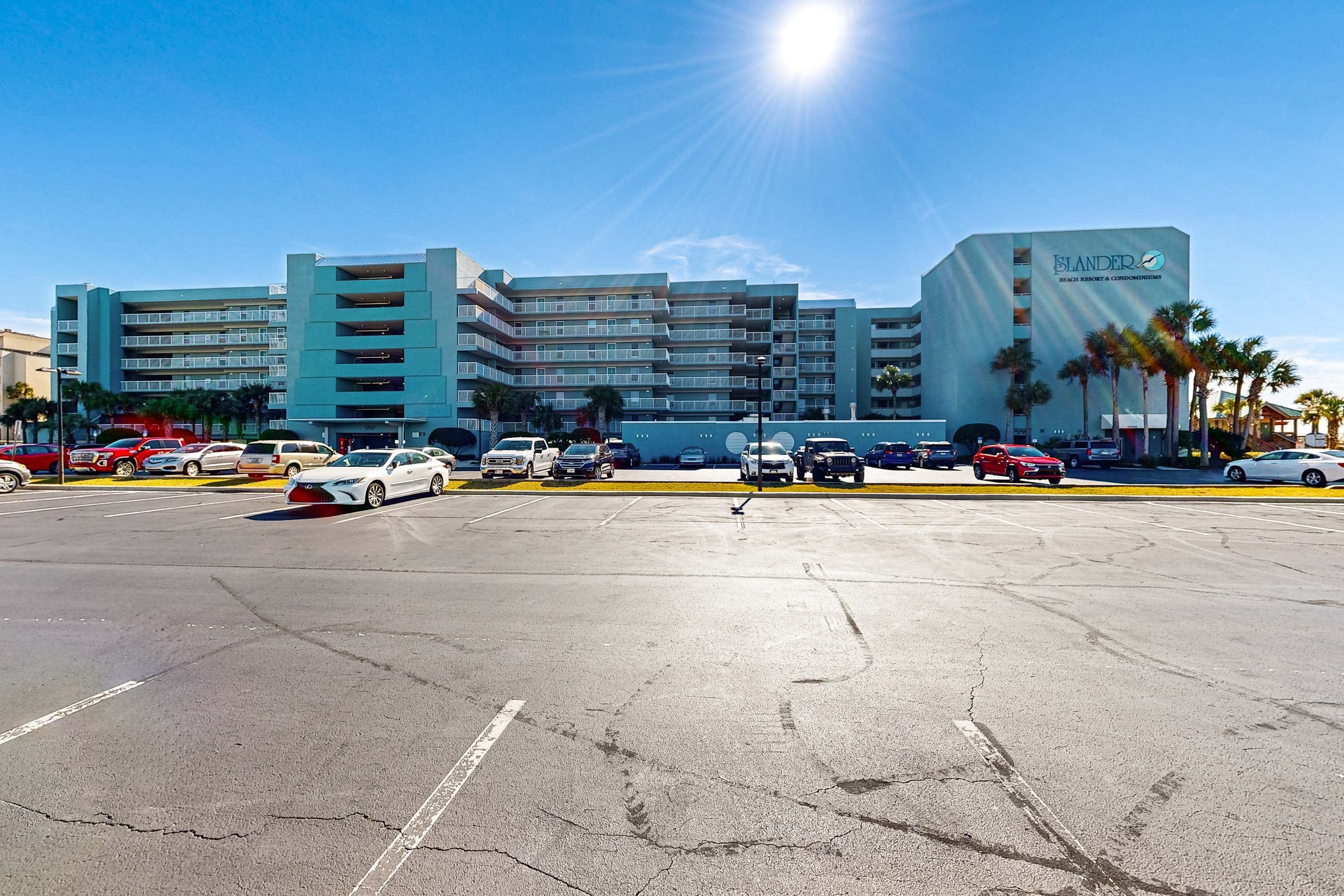 A multi-story hotel with a parking lot in front.
