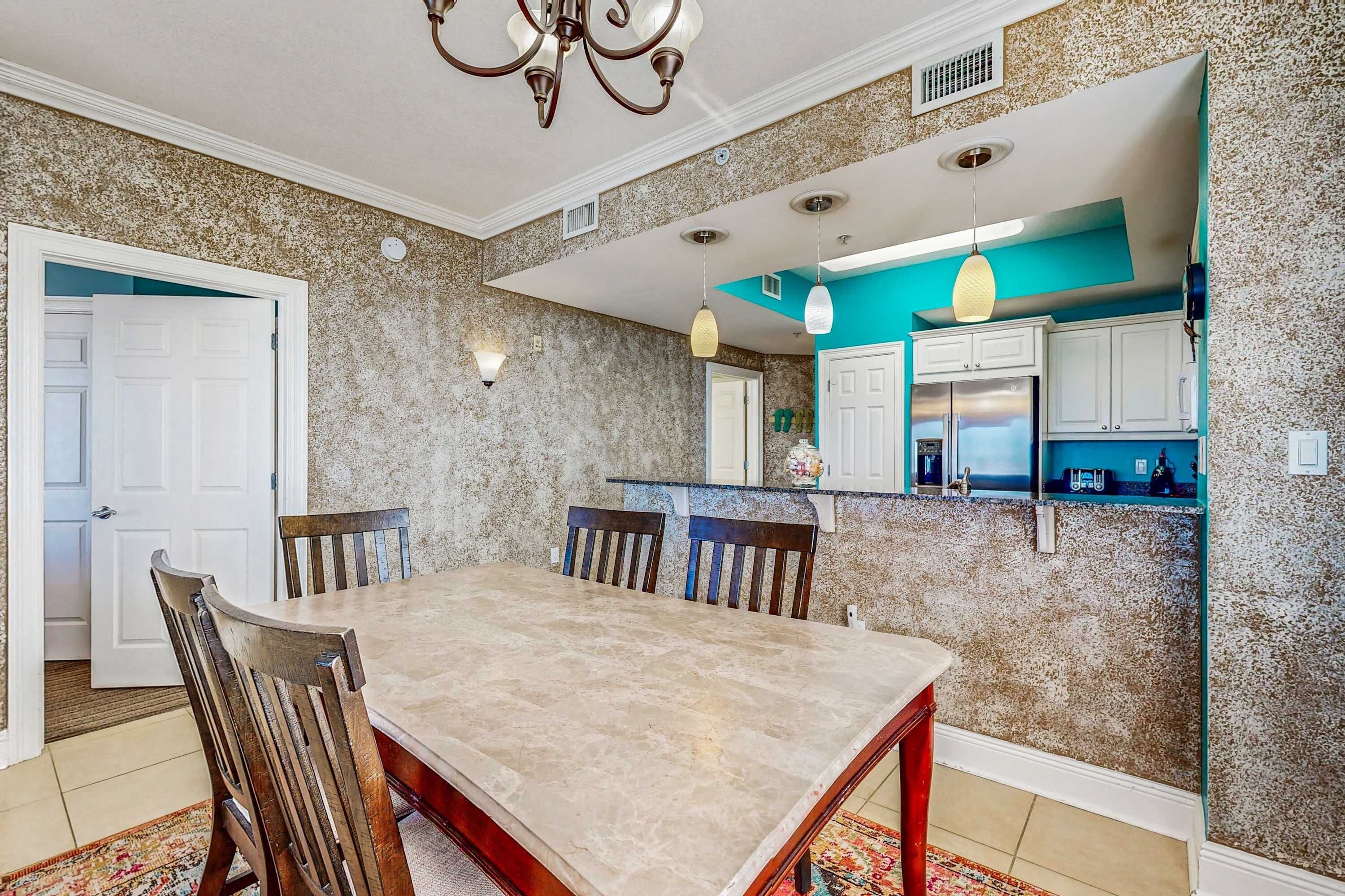 A dining area with a marble table, wooden chairs, and a chandelier.