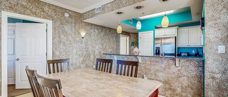A dining area with a marble table, wooden chairs, and a chandelier.