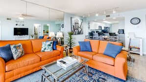 Een moderne woonkamer met twee oranje banken, een salontafel en een grote spiegel.
