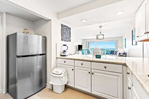 A modern kitchen with a stainless steel refrigerator, white cabinetry, and a view to the outside. - Second-Floor Gulf-front Condo with Beach Service & pool (Miramar Beach)