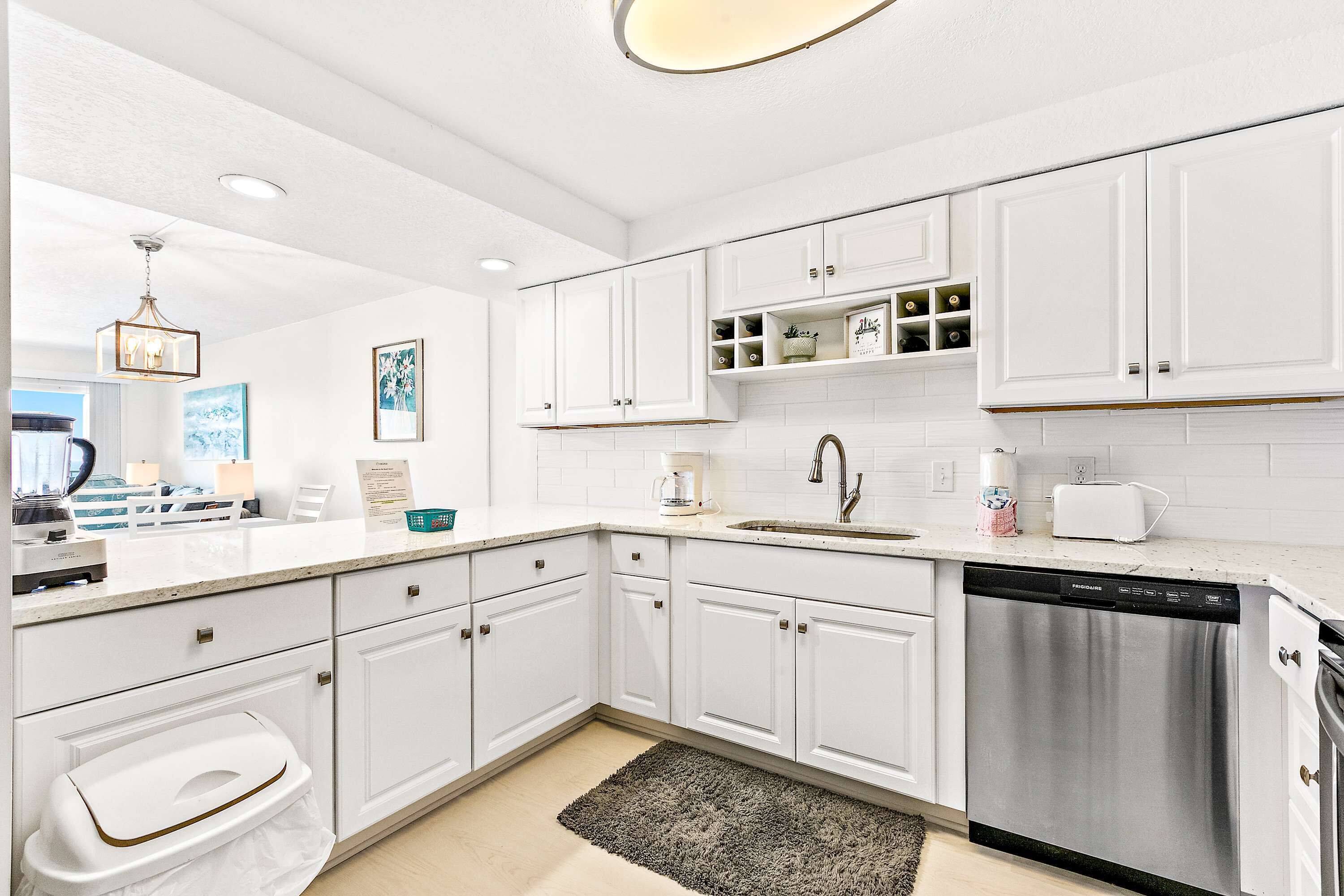 A modern kitchen with white cabinetry, a stainless steel dishwasher, and a coffee maker.