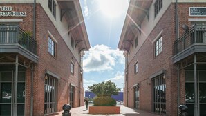 A symmetrical street view with brick buildings, a central tree, and a clear sky. - Stylish, dog-friendly townhome with firepit & enclosed yard - blocks to downtown (Pensacola)