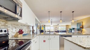 Una cocina moderna con armarios blancos, encimera de granito y electrodomésticos de acero inoxidable.