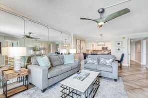 A spacious living room with two grey sofas, a coffee table, and a ceiling fan. - Snowbird-friendly Gulf-front Condo with outdoor Pool, Gym, Tennis (Miramar Beach)