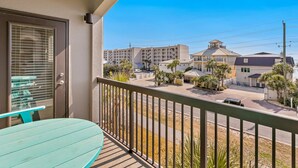 Un balcón con vista a una zona residencial, que incluye edificios y una calle.