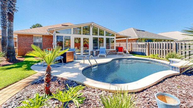 Ein Garten mit Swimmingpool, einer überdachten Terrasse und einem Ziegelhaus.