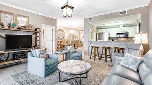 A living room with a TV, sofas, and a coffee table. - 4th Floor Bayfront Condo With Private W/D & Shared Outdoor Pool (Pensacola Beach)