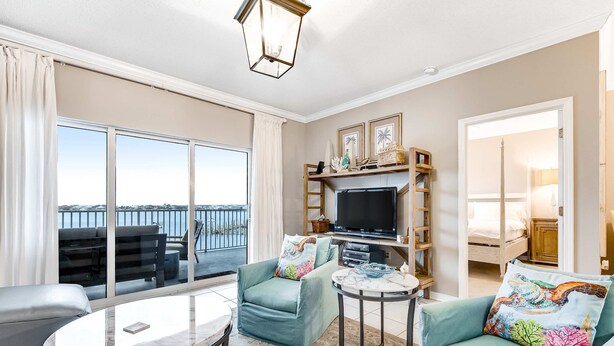 A spacious living area with a balcony, a television, and comfortable seating. - 4th Floor Bayfront Condo With Private W/D & Shared Outdoor Pool (Pensacola Beach)