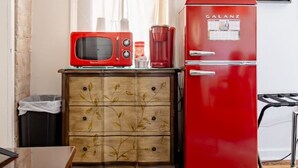 Une cuisine compacte avec un réfrigérateur rouge, un four à micro-ondes et un meuble avec des tiroirs.
