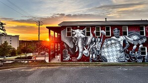 Une fresque murale orne un bâtiment, avec un coucher de soleil en arrière-plan.
