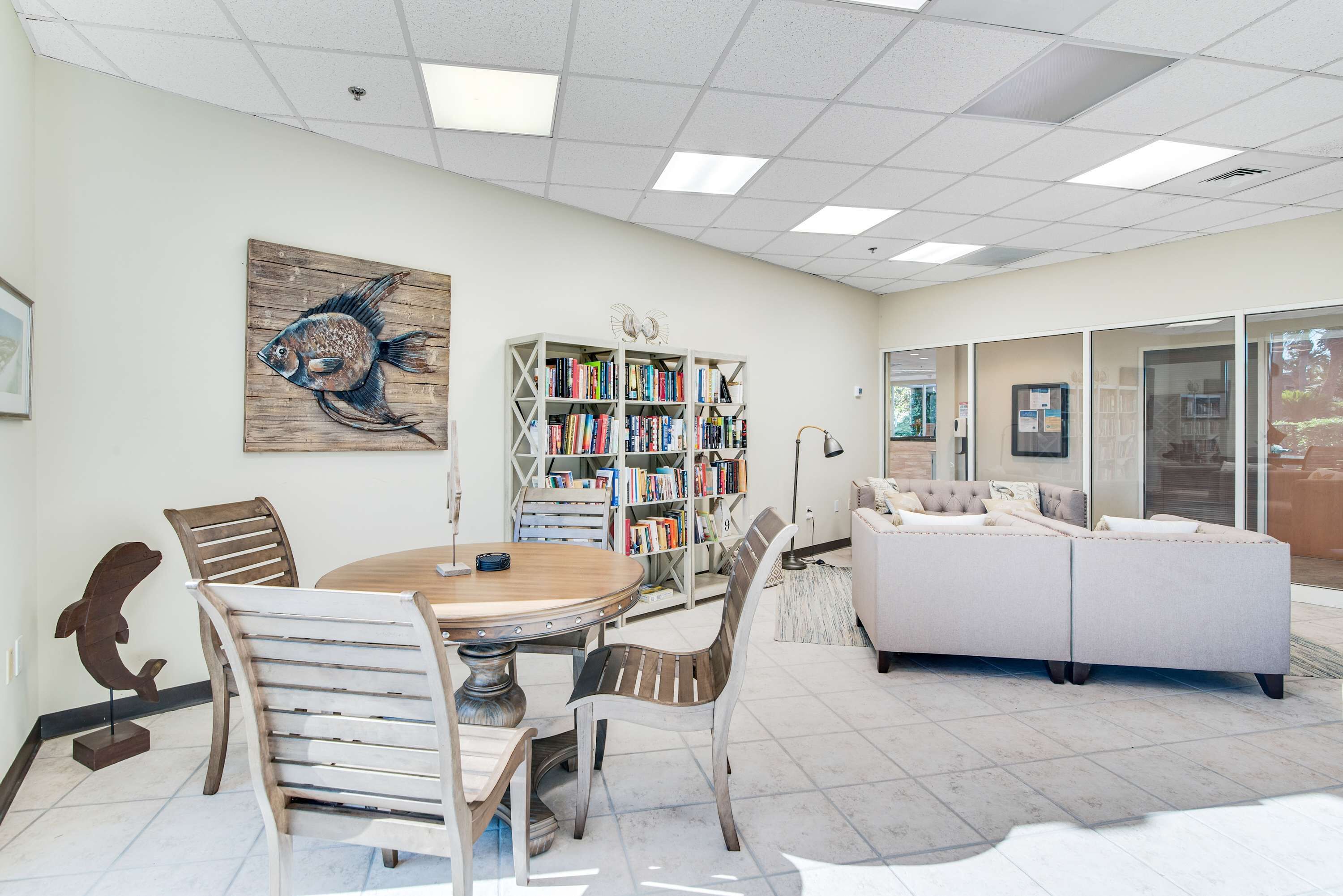 Une pièce bien éclairée, avec une table à manger en bois, des chaises, une bibliothèque et un canapé.