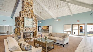 A spacious living area with a stone fireplace, a sofa, a coffee table, and a view of the outside. - Fifth-floor, oceanfront condo with fast WiFi & pool  -  snowbirds OK (Miramar Beach)