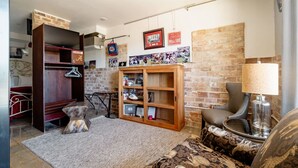 Ein gemütliches Wohnzimmer mit Backsteinwand, einem Holzregal, einem gemusterten Sofa und einer Lampe.