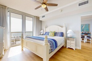 Une chambre dotée d’un grand lit, d’un ventilateur de plafond, d’un bureau avec une chaise et offrant une vue sur l’extérieur.