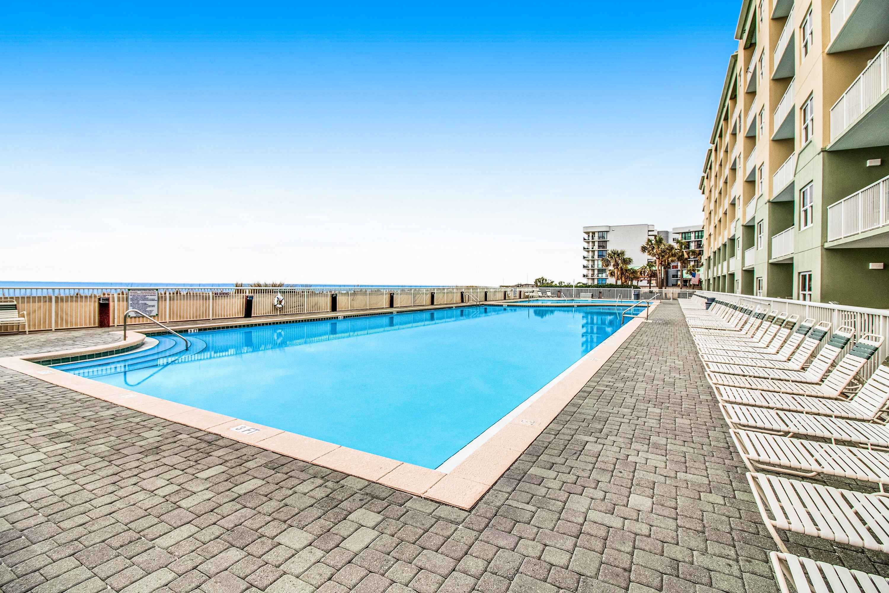 Une piscine avec des chaises longues et vue sur l’océan.