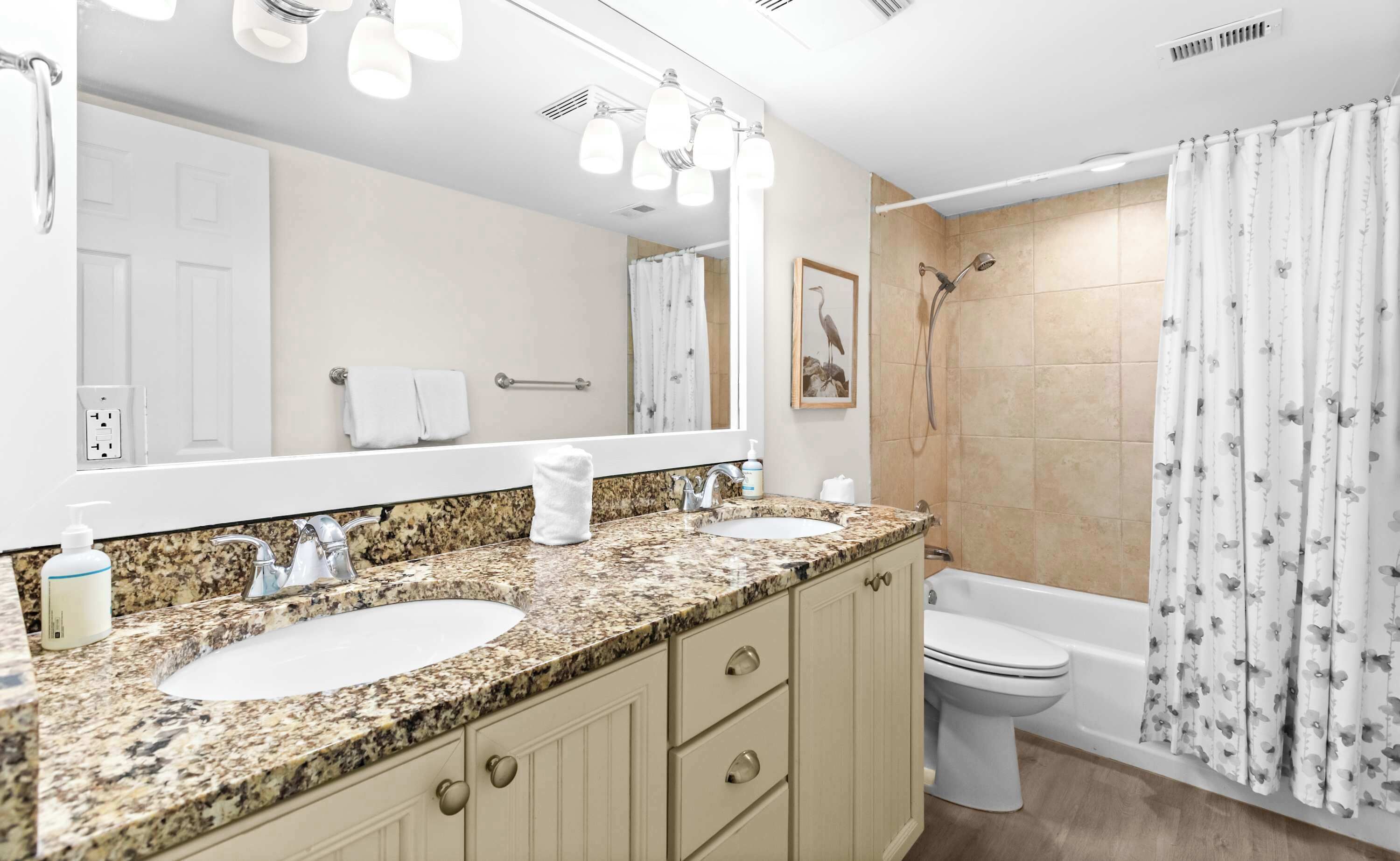 A bathroom with two sinks, a toilet, a shower, and a large mirror.