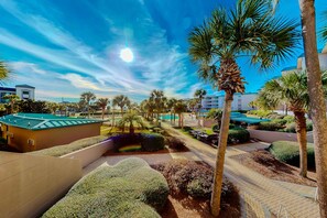 A resort area with palm trees, a pool, and a well-maintained garden. - Ocean view condo with high-speed WiFi, balcony, shared pool, & beach access (Miramar Beach)