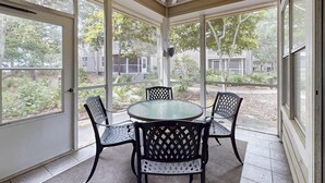 A covered patio with a round table and four chairs, large windows, and a ceiling fan. - Modern Resort Home with Shared Hot Tub, Pool, Free WiFi, and Beach Access (Miramar Beach)