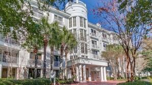 A multi-story hotel with a central circular tower, balconies, and a covered entrance. - Upscale studio at The Village of Baytowne Wharf with AC, pool, hot tub & gym (Miramar Beach)