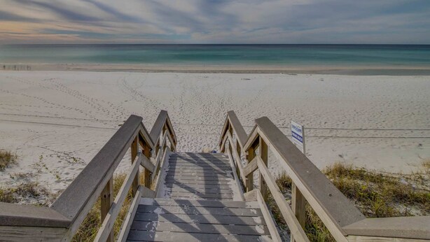 A wooden staircase leading to a beach with a clear view of the ocean. - Upscale studio at The Village of Baytowne Wharf with AC, pool, hot tub & gym (Miramar Beach)