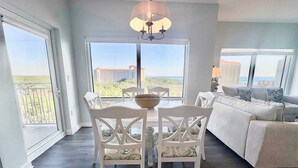 Amplia sala de estar con comedor, ventanas grandes que ofrecen vista a la ciudad y un balcón.