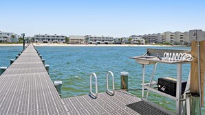 Eine Steg, der sich in ruhiges Wasser erstreckt, mit einer Reihe von Gebäuden im Hintergrund.