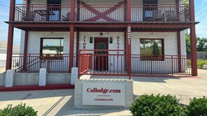 A two-story building with a balcony and a sign that reads "Collodge.com A Boutique Hotel".