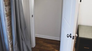 A narrow hallway with a wooden floor leading to a closet with a white door.