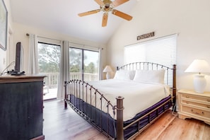 A bedroom with a bed, bedside lamps, a ceiling fan, a dresser, and a balcony with a view. - Dog-friendly home near the beach with beach gear, on-site pool & tennis (St. George Island)