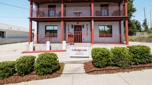 A two-story building with a red and white color scheme, a sign reading "Collodge.com", and a small front garden. - Alabama Boutique Hotel: #6 w/ TV Rm, PacMan Arcade (Tuscaloosa)