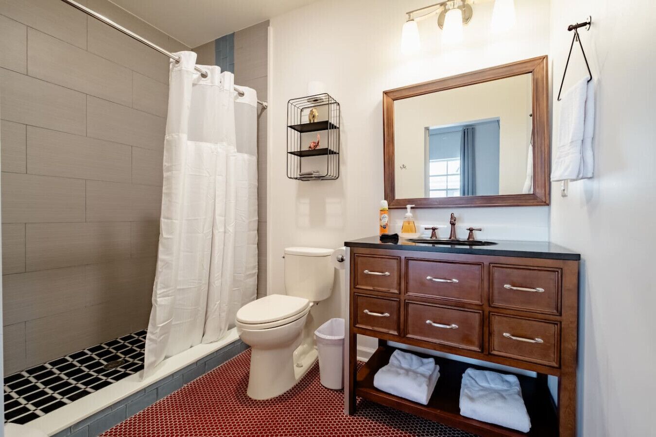 Une salle de bain comprenant une douche, des toilettes, un meuble-lavabo avec des tiroirs, un miroir et un porte-serviettes.