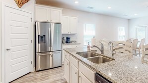 Una cocina moderna con armarios blancos, electrodomésticos de acero inoxidable y encimera de granito.