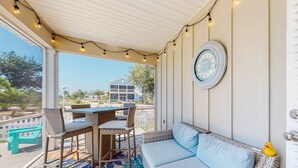 Un espacio de estar al aire libre cubierto con mobiliario de mimbre, un reloj y luces colgantes.