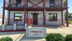 Un edificio a due piani con un balcone, un cartello con su scritto “Collodge.com A Boutique Hotel” e un tetto rosso.