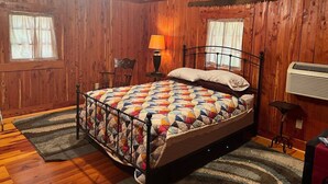 Un dormitorio con paneles de madera, una cama, una araña y un calefactor.