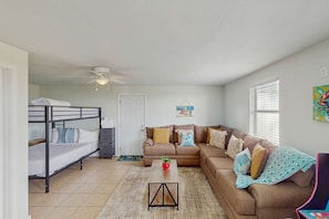 A compact living space with a bunk bed, a sofa, a coffee table, and a ceiling fan. - Coastal escape with bay views, fishing, Washer / dryer, and Wifi (Eastpoint)